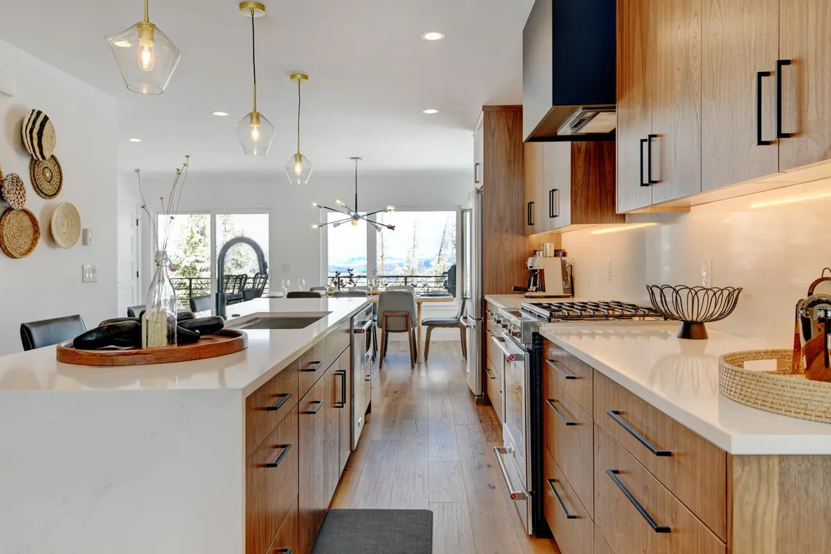 A stylish open kitchen and dining area with a prominent kitchen island, contemporary cooking range, and large windows that fill the space with natural light. The layout encourages social cooking and gathering, with views that hint at sunsets and shared meals.