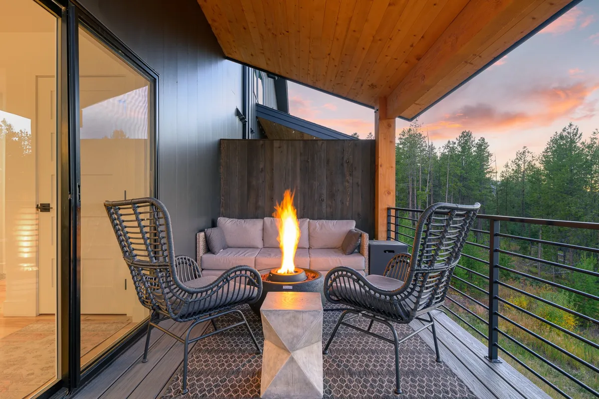 A tranquil exterior seating area surrounded by trees, centered on a fire pit, perfect for relaxing or socializing as the sun sets. The natural setting hints at nearby trails and the peaceful retreat that awaits after a day of exploration.