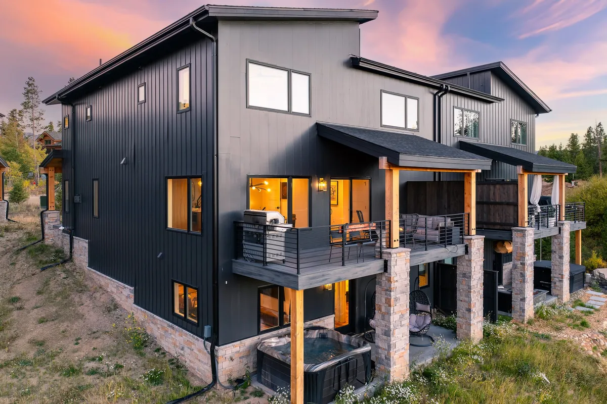 A spacious balcony and patio area featuring a hot tub, outdoor seating, and large windows overlooking landscaped surroundings. The spot encourages both relaxation and socializing, with easy access to nature trails visible in the background, and ample space for hosting gatherings or quiet moments with coffee.